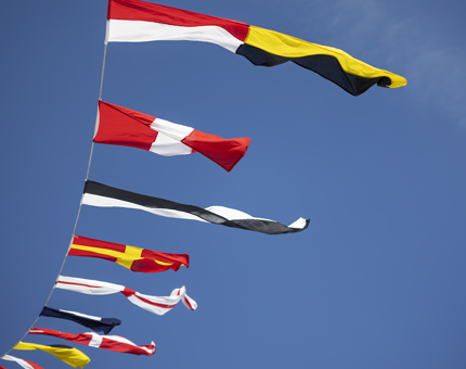 Colourful dress flags flying in the wind against a blue sky.